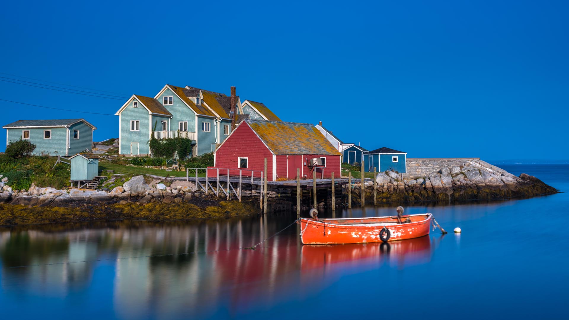 colourful buildings of peggy's cove nova scotia with a boat in the harbour