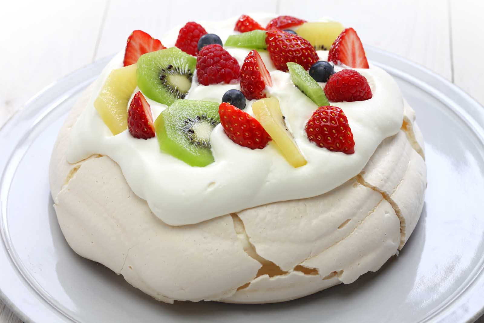 pavlova topped with whipped cream and fruit