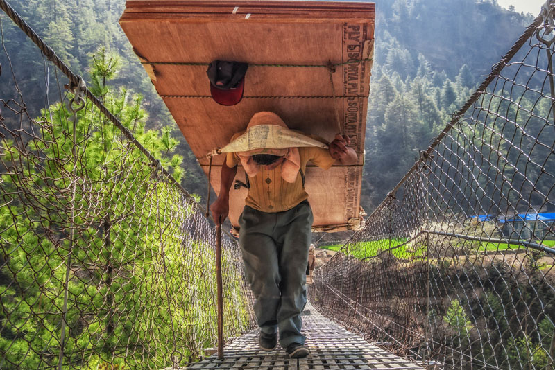 base camp trek photos porter on bridge