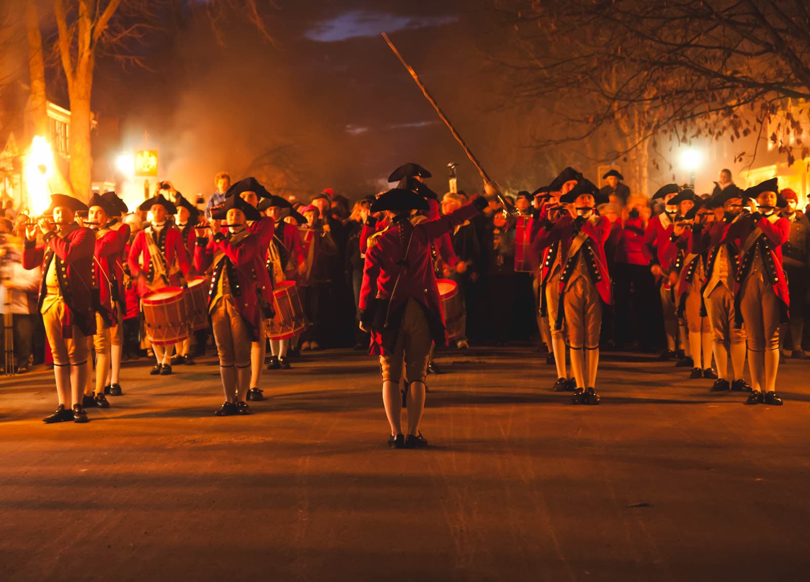 21 Best Places to Visit in December in the USA (2025 Edition) A historic street in Colonial Williamsburg at night, with real candles glowing in the windows of the buildings.