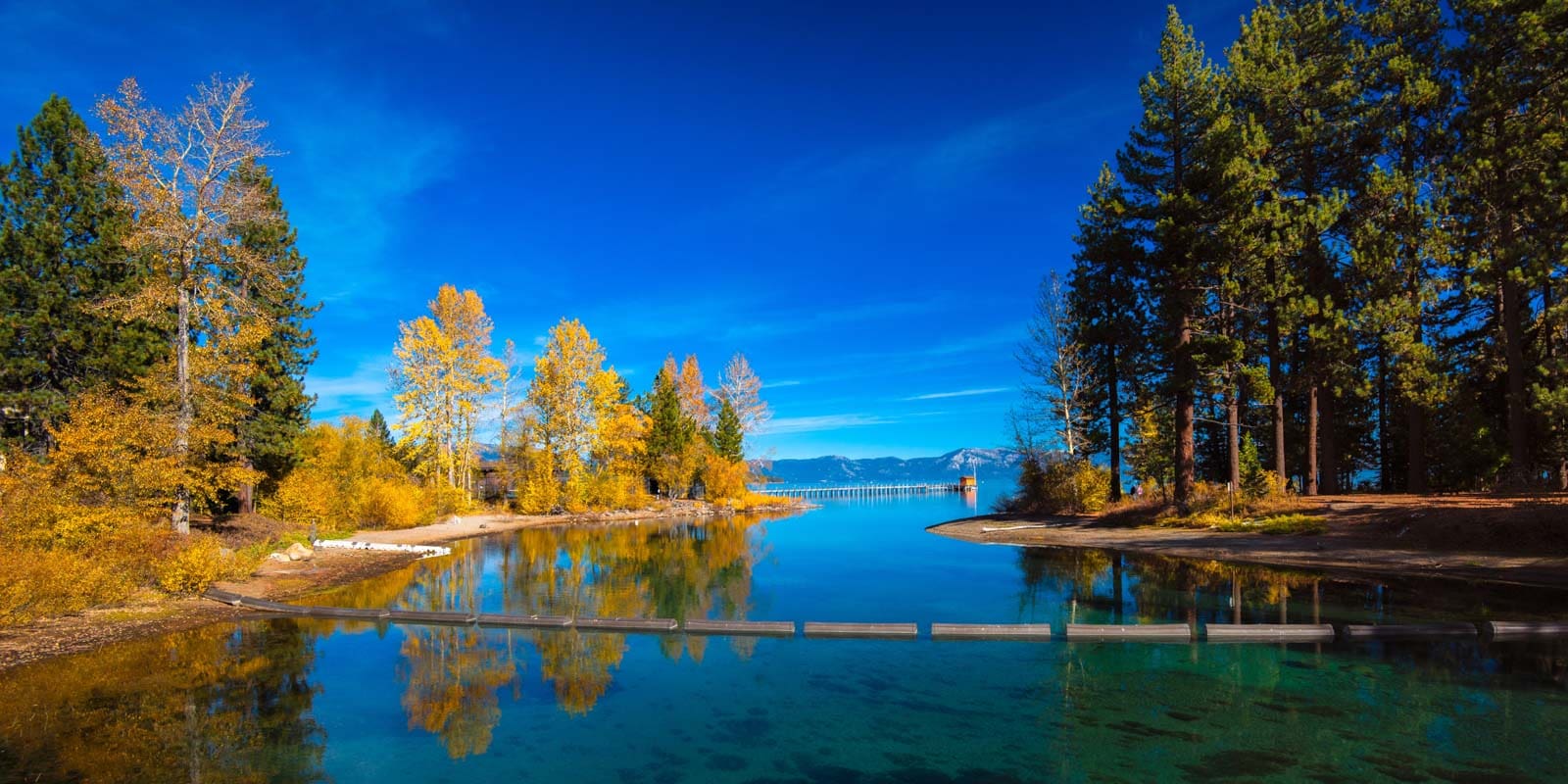 A wide view of Emerald Bay in Lake Tahoe with snow-dusted mountains, a beautiful destination to visit in November in the USA.