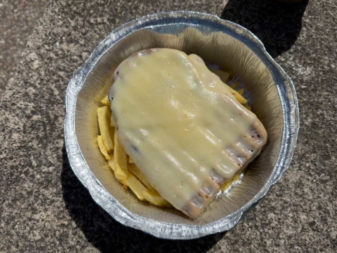 The iconic Francesinha sandwich from Porto, covered in melted cheese and a rich beer sauce.