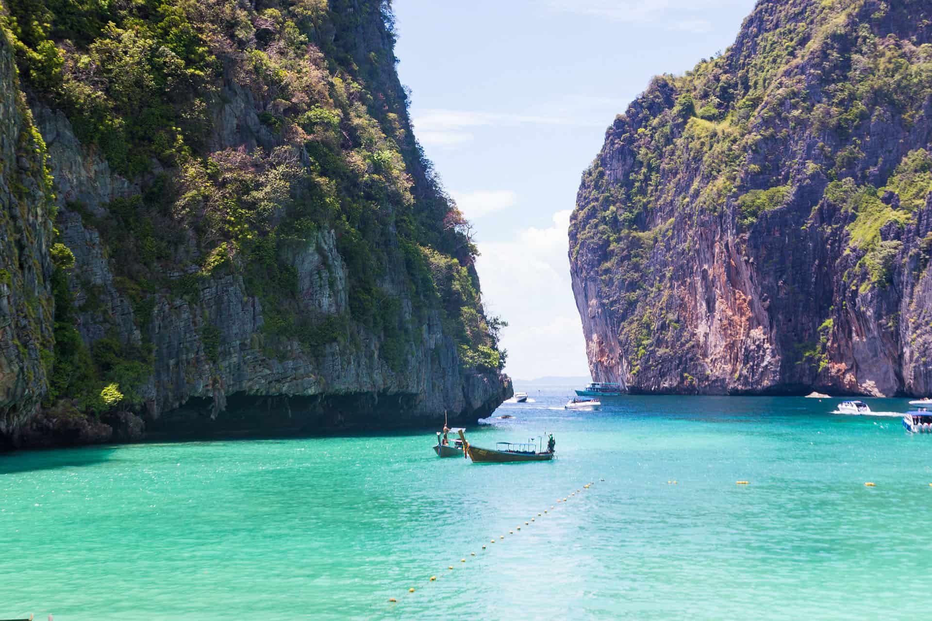 limestone cliffs of thailand beaches with longtail boats