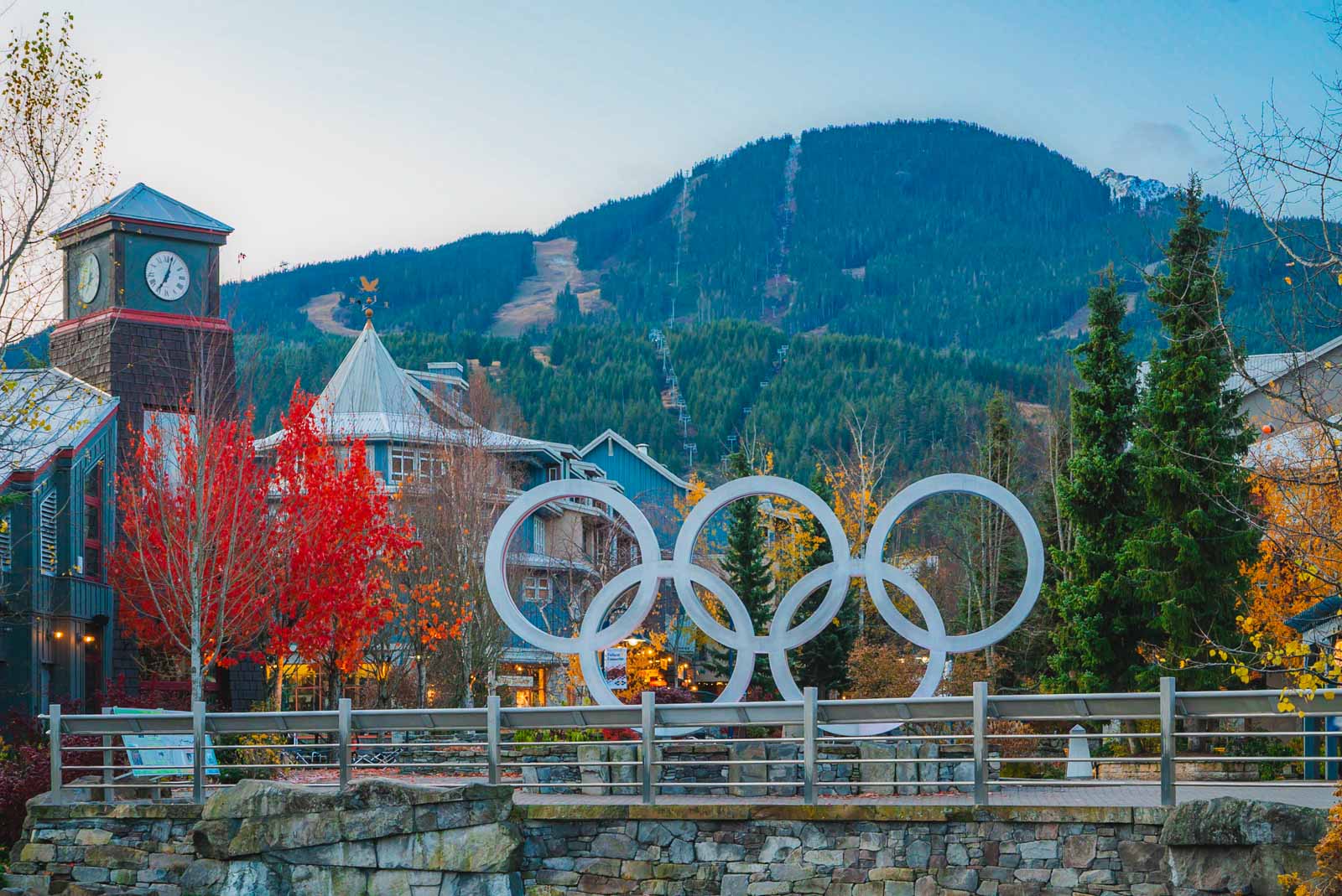People walking along the pedestrian-only stone streets of Whistler Village with chalet-style buildings and mountains.
